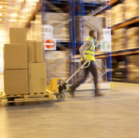 Blurred view of worker carting boxes in warehouse